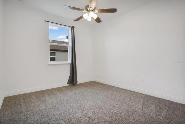 an empty room with a window and a fan