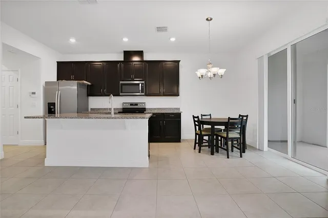 a kitchen with kitchen island granite countertop stainless steel appliances a table and chairs in it