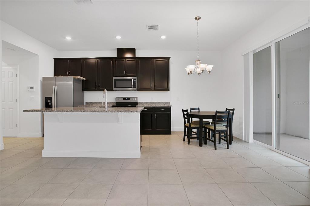 2460 Firstlight Way Winter Park, FL 32792 - Photo 5 of 24 a kitchen with kitchen island granite countertop stainless steel appliances a table and chairs in it