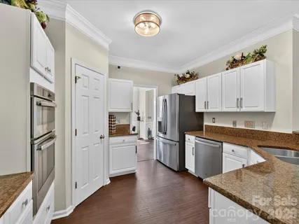 a kitchen with stainless steel appliances granite countertop a refrigerator a stove and a sink with wooden floor