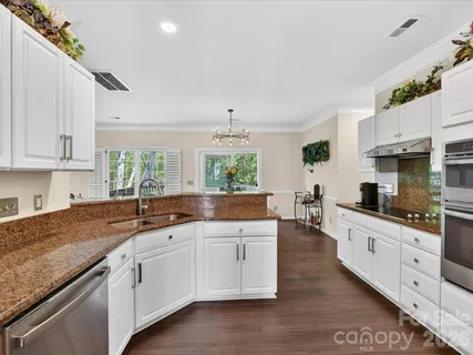 a kitchen with granite countertop a sink white cabinets and white appliances