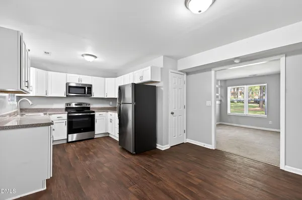 a kitchen with granite countertop stainless steel appliances a refrigerator cabinets and wooden floor