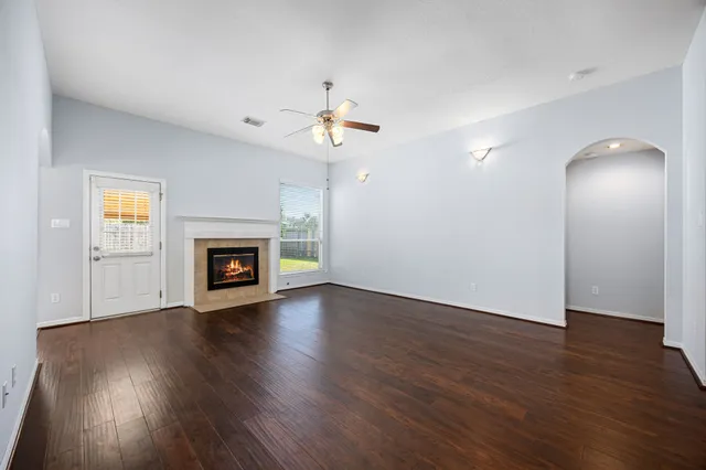 an empty room with wooden floor fireplace and a window