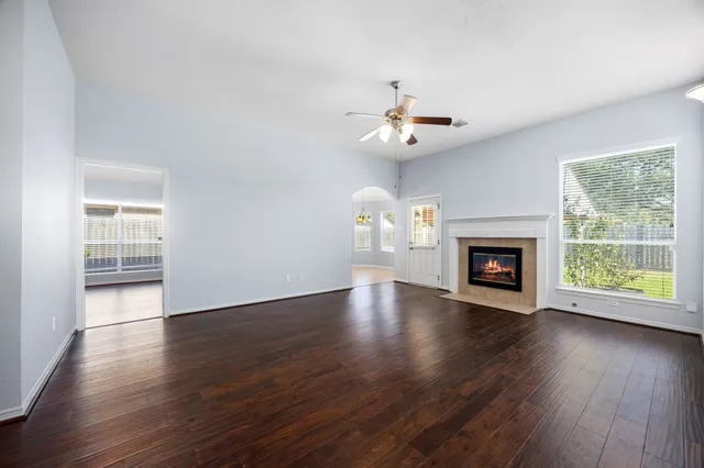 a view of an empty room with wooden floor a fireplace and a window