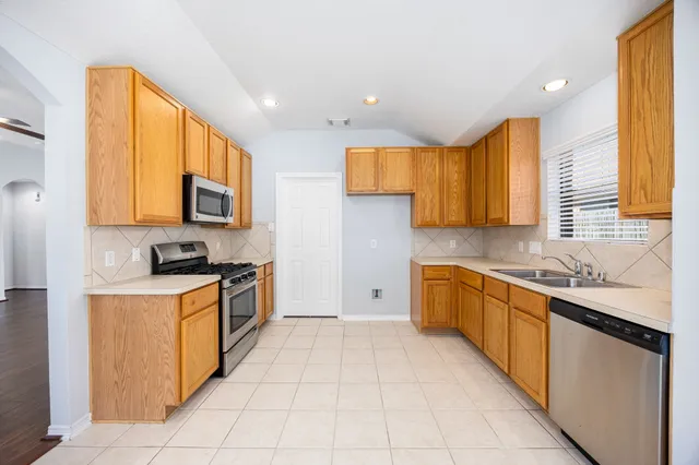 a kitchen with stainless steel appliances granite countertop a stove top oven a sink dishwasher and a refrigerator
