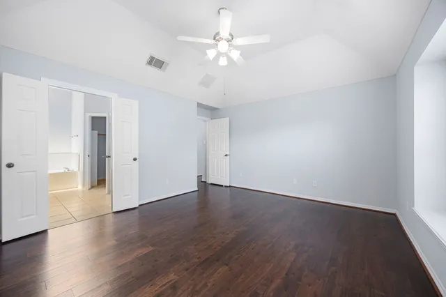 an empty room with wooden floor and fan