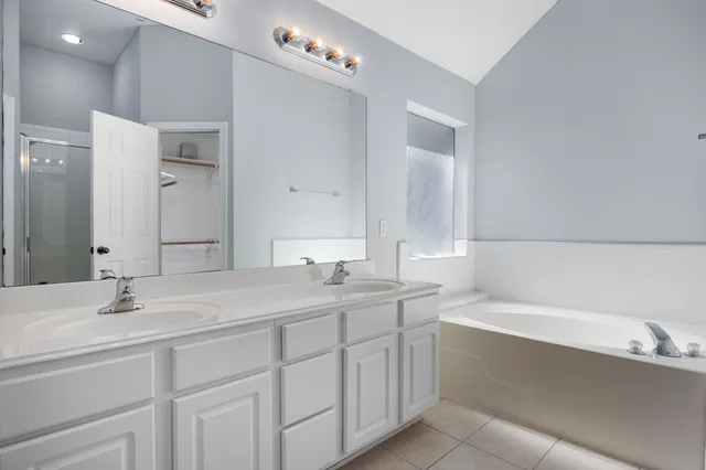 a bathroom with a sink double vanity granite tub shower and a mirror