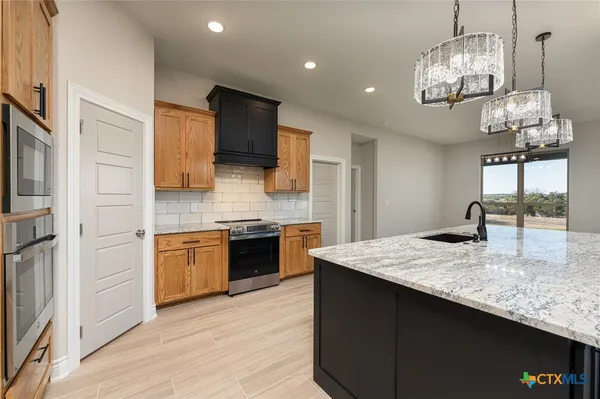 a kitchen with stainless steel appliances granite countertop a sink refrigerator and cabinets