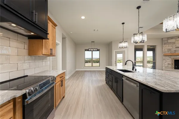 a kitchen with granite countertop a stove a sink dishwasher and a wooden cabinets