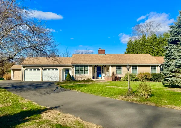 a view of a white house with a big yard and potted plants and large trees