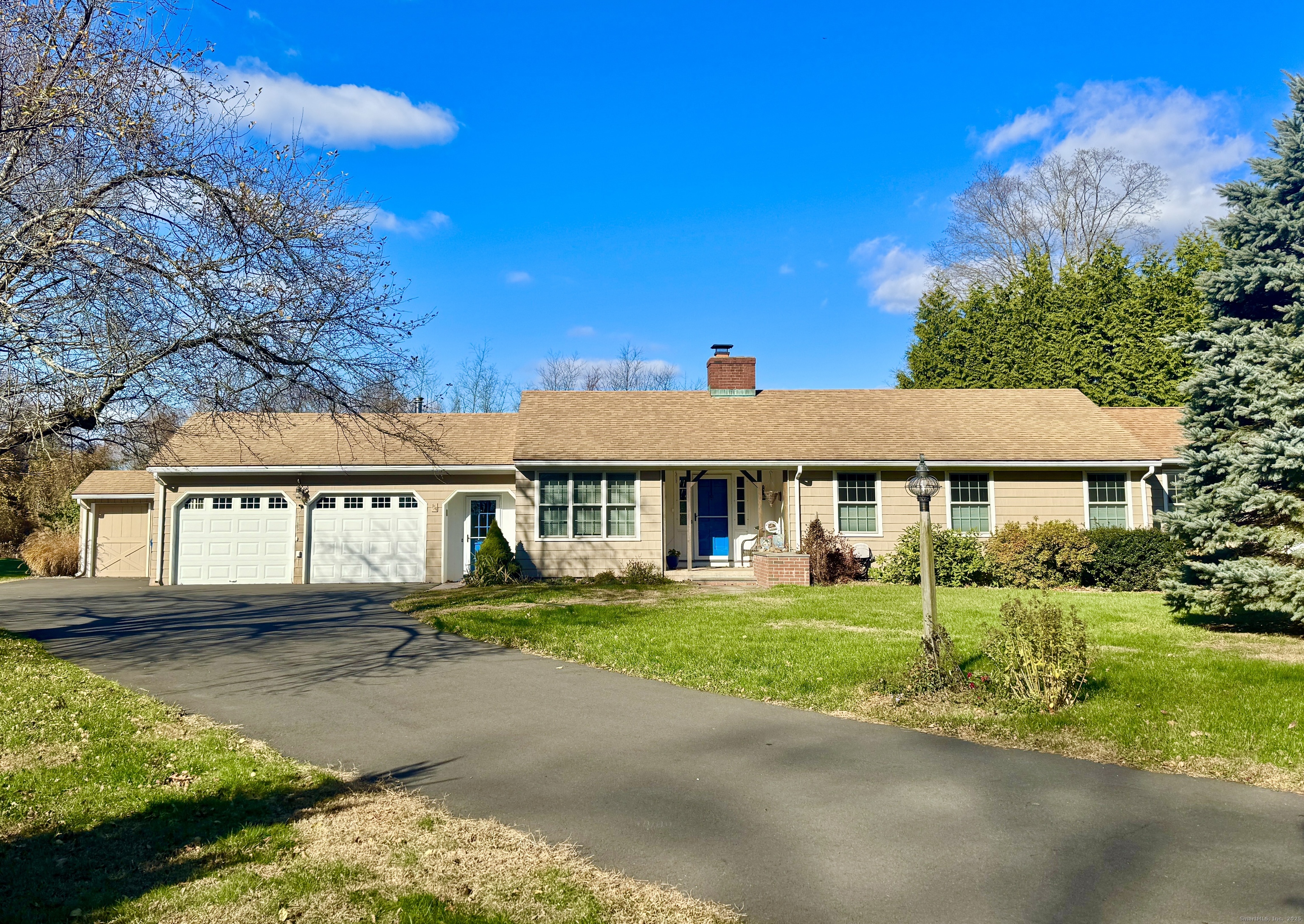 a view of a white house with a big yard and potted plants and large trees