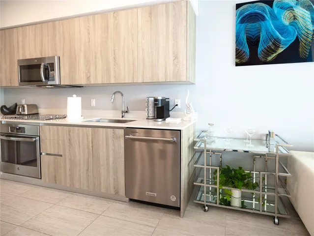 a living room with stainless steel appliances furniture and a kitchen view