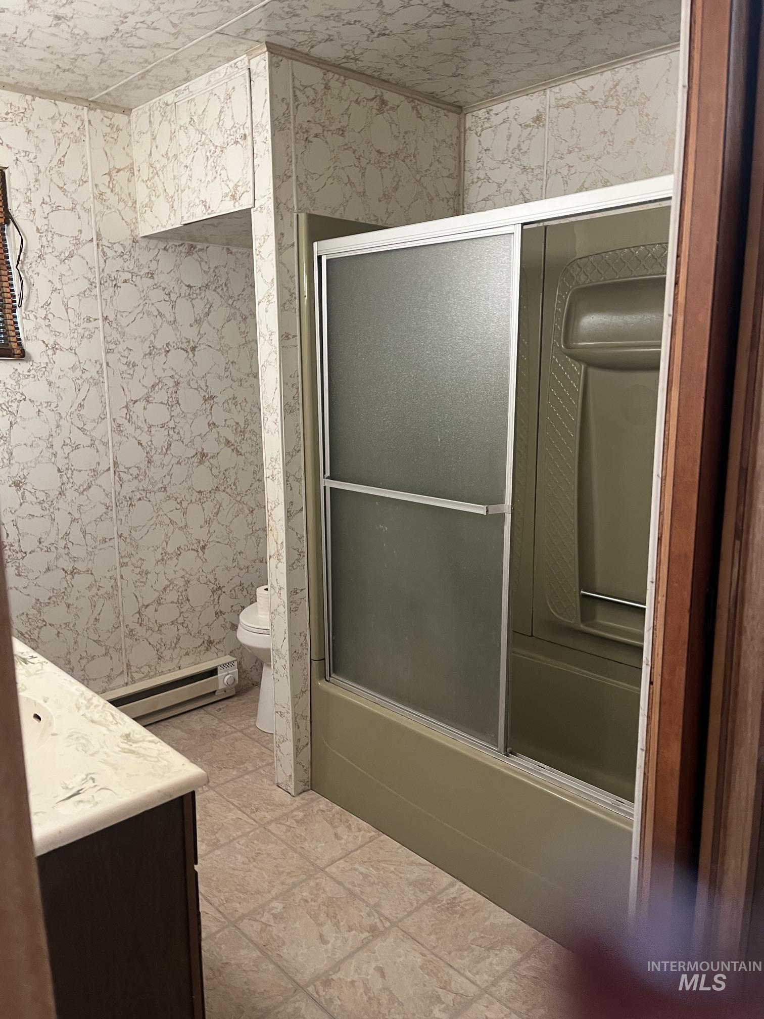 39 Mayflower Mine Road Placerville, ID 83666 - Photo 21 of 36 Enclosed shower with sliding glass doors, patterned wall paneling, and a floor-mounted toilet