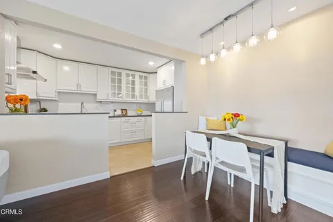 a kitchen with stainless steel appliances a refrigerator a stove a dining table and chairs with wooden floor