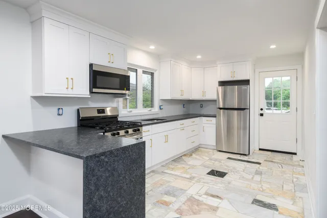 a kitchen with granite countertop a refrigerator stove top oven and sink