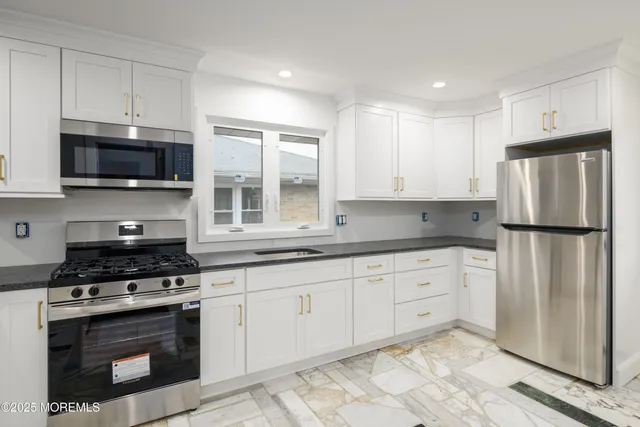 a kitchen with stainless steel appliances granite countertop a stove a refrigerator and a microwave