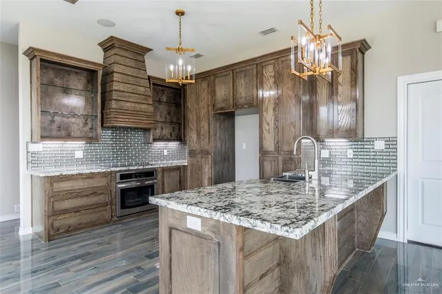 a kitchen with kitchen island granite countertop a sink and a wooden floor