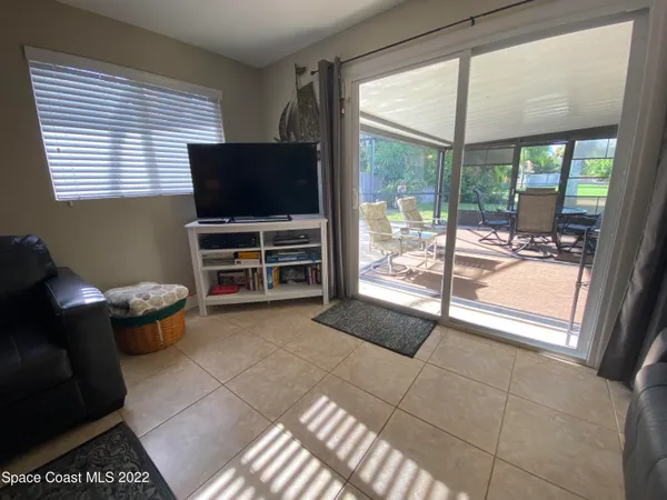 a living room with furniture a flat screen tv and floor to ceiling window