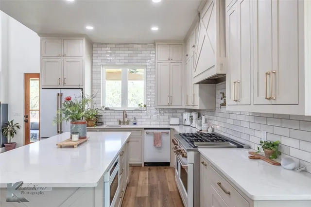 a kitchen with stainless steel appliances a sink a stove top oven a counter space and cabinets