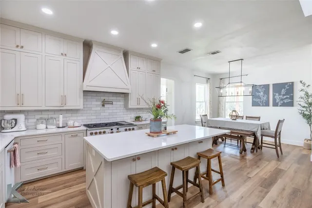 a kitchen with a dining table chairs sink and cabinets