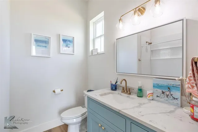 a bathroom with a granite countertop sink a toilet and a mirror