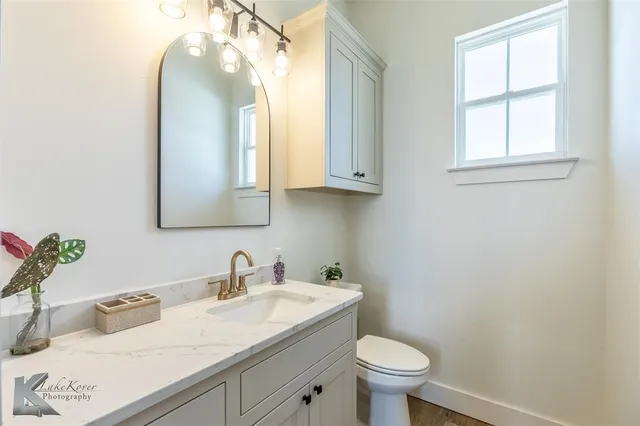 a bathroom with a granite countertop toilet sink and mirror