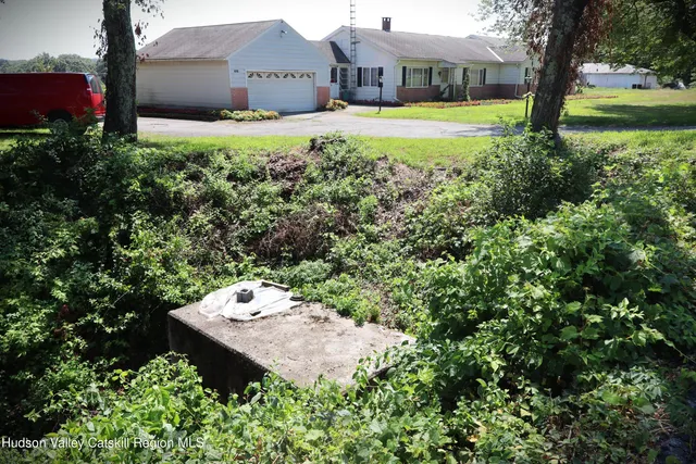 a view of a house with a yard and large trees