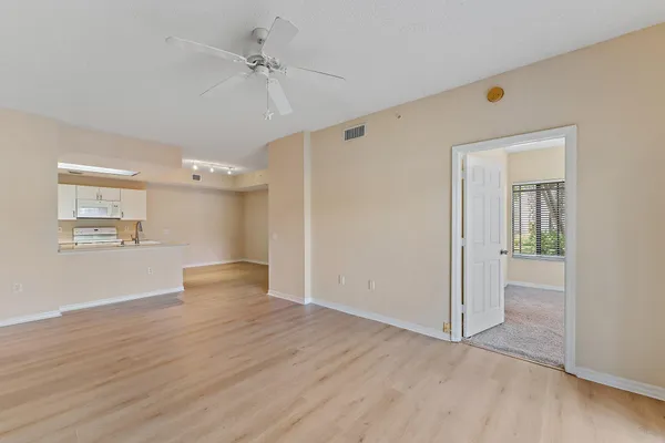 a view of empty room with wooden floor and fan