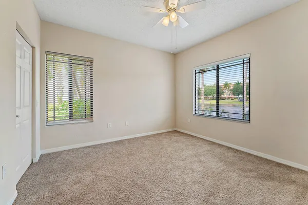 an empty room with windows and fan