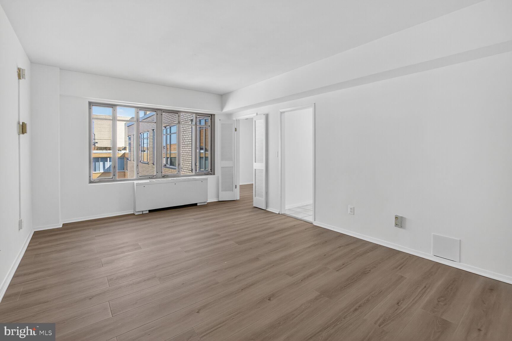 1711 Massachusetts Avenue Northwest, Unit 825 Washington, DC 20036 - Photo 4 of 16 a view of an empty room with wooden floor and a window