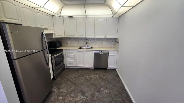 a kitchen with stainless steel appliances granite countertop a refrigerator a sink a stove and white cabinets
