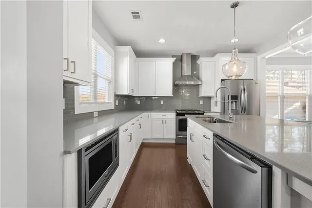 a kitchen with stainless steel appliances granite countertop a sink a stove and a refrigerator