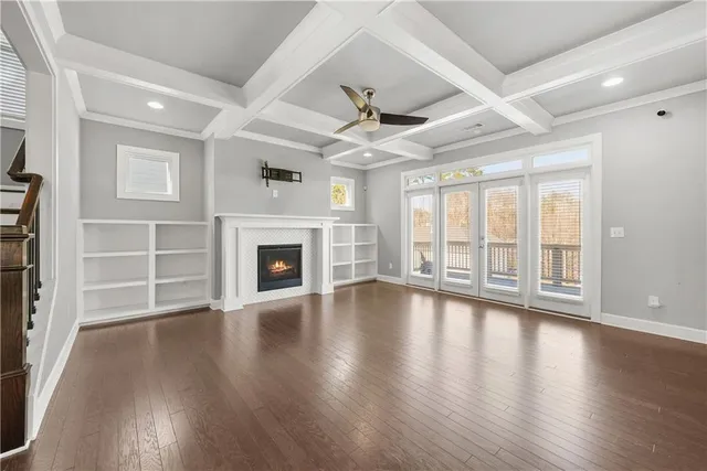 an empty room with wooden floor fireplace and windows