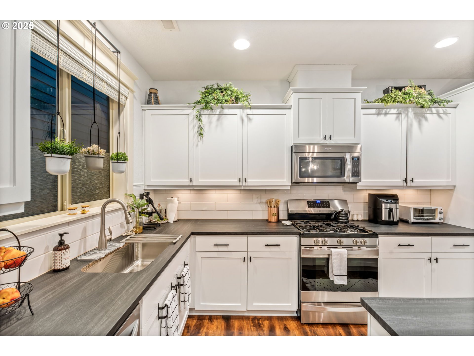 8826 Southwest Spruce Street Portland, OR 97223 - Photo 5 of 34 a kitchen with granite countertop a sink stainless steel appliances and white cabinets