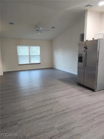 an empty room with wooden floor cabinet and windows