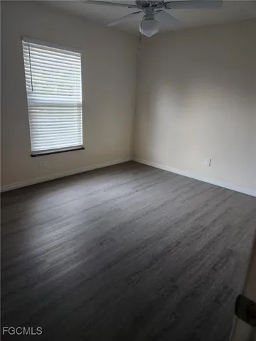 an empty room with wooden floor cabinet and windows