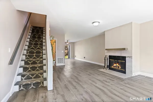 a view of an empty room with wooden floor fireplace and a window