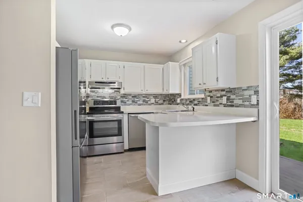 a kitchen with stainless steel appliances a sink stove and white cabinets