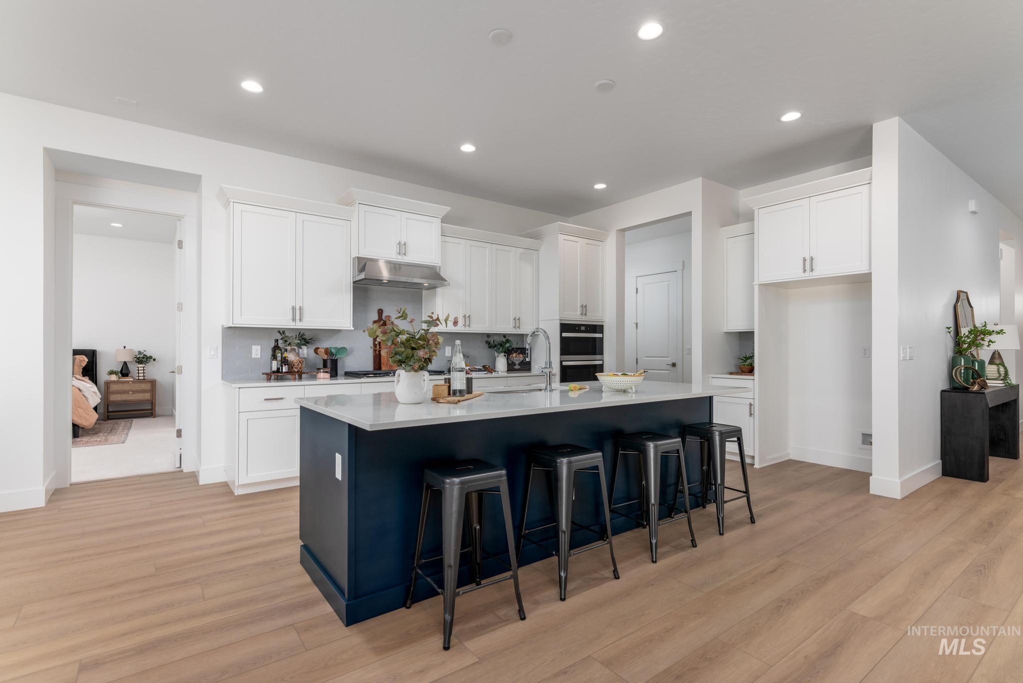 9074 West Moonglade Street Star, ID 83669 - Photo 10 of 40 Contemporary kitchen featuring a large central island with a deep blue base and light-toned countertop, white cabinetry with brushed nickel hardware, stainless steel appliances, and recessed lighting