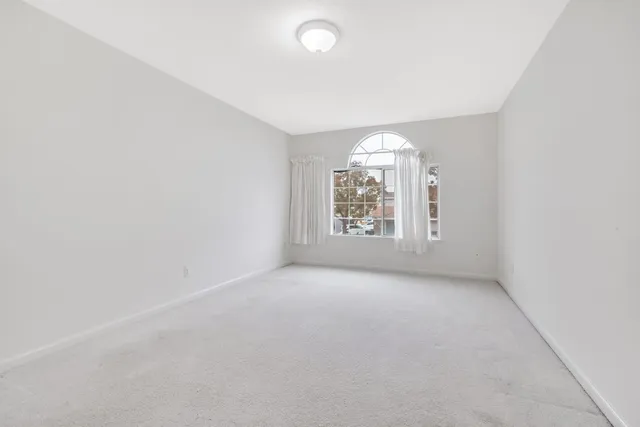 an empty room with windows and chandelier fan