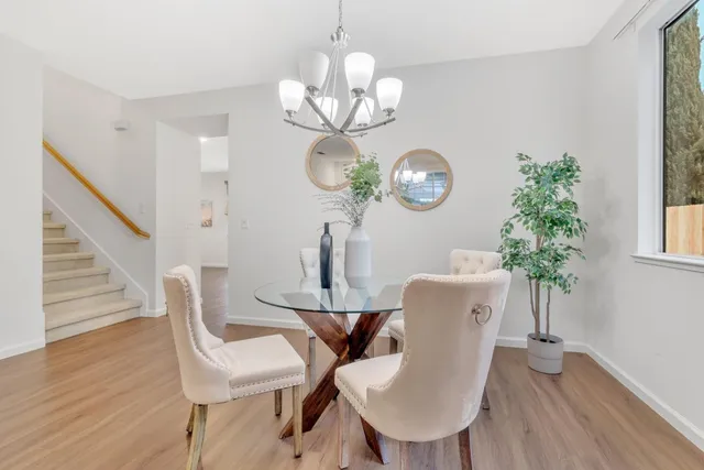 a dining room with wooden floor a chandelier a glass table and chairs
