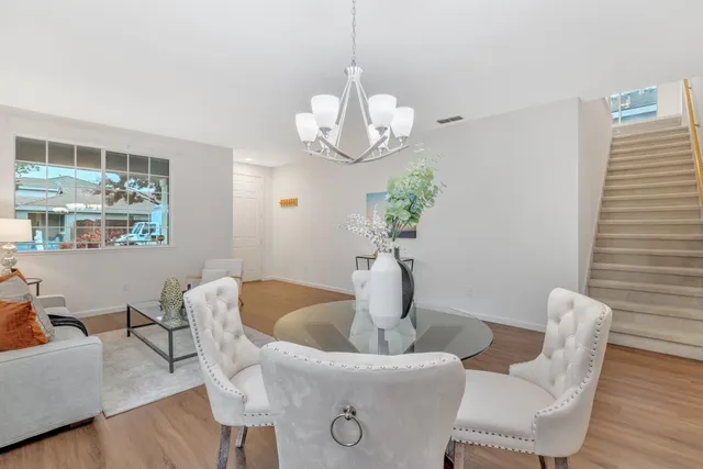 a dining room with wooden floor a chandelier a glass table and chairs