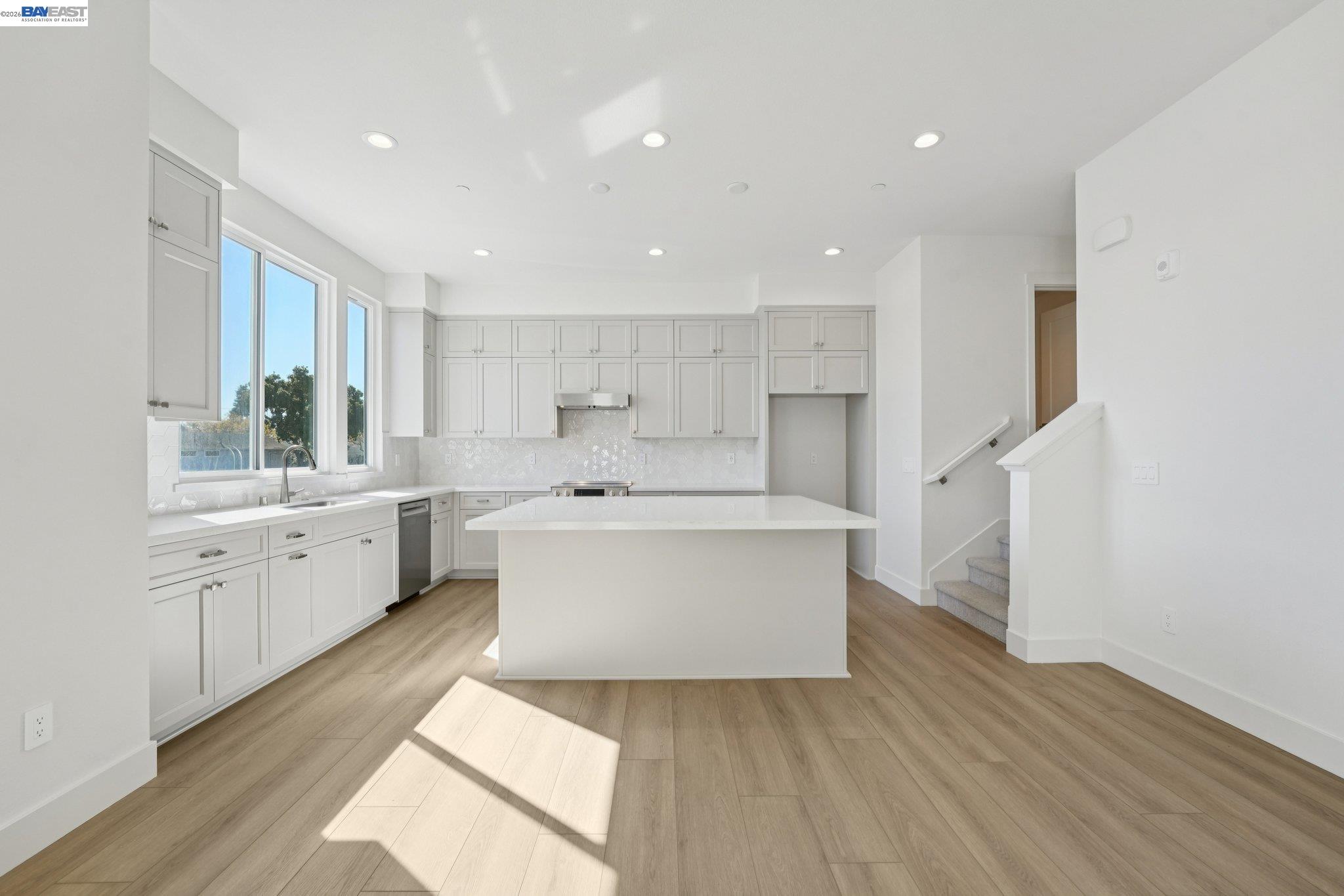 1933 Grand Street Alameda, CA 94501 - Photo 1 of 50 a large white kitchen with wooden floors and white stainless steel appliances