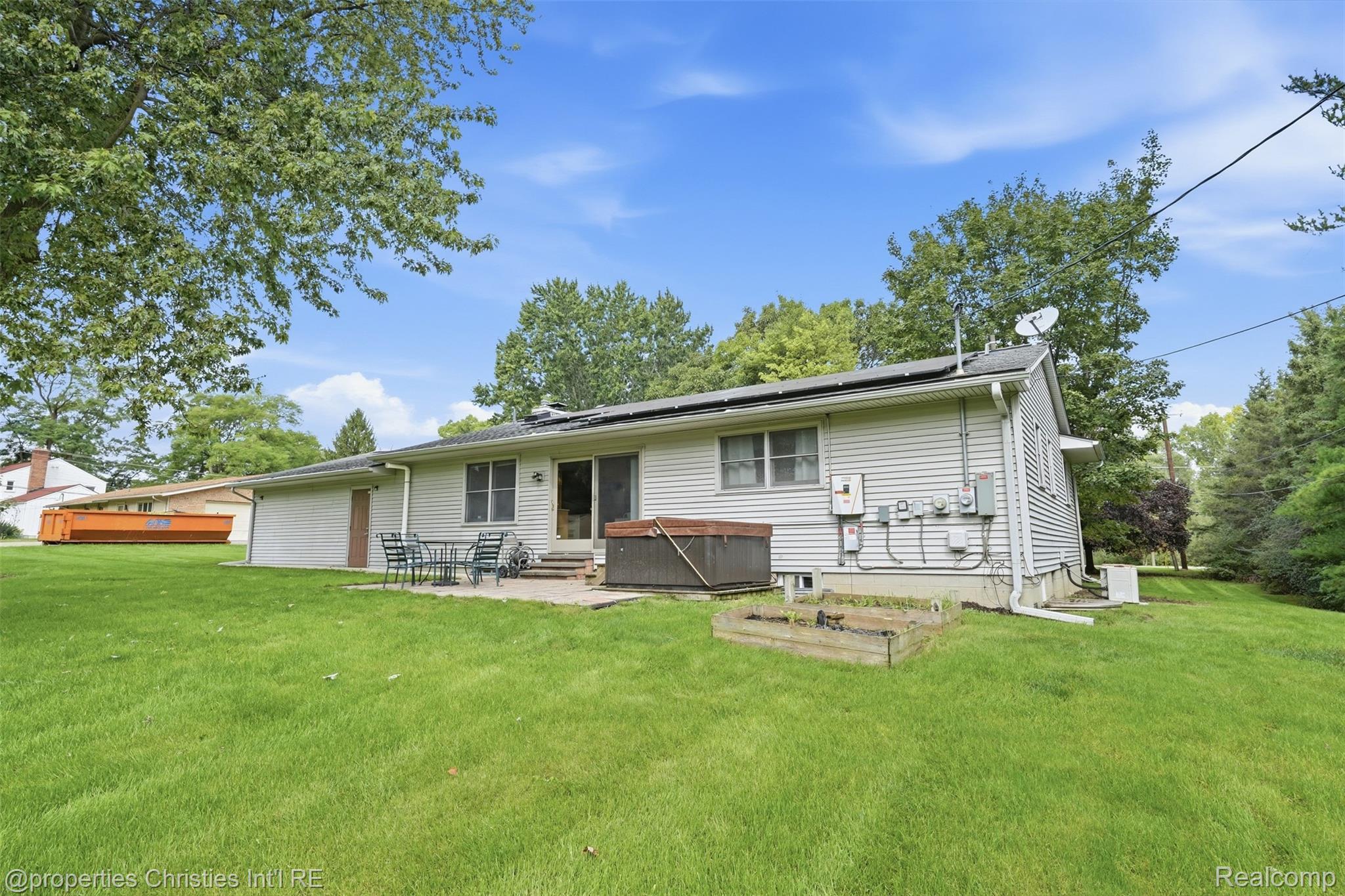 4030 Textile Road Ypsilanti, MI 48197 - Photo 40 of 58 Spacious rear lawn with mature trees, a stone patio, and sliding glass door access