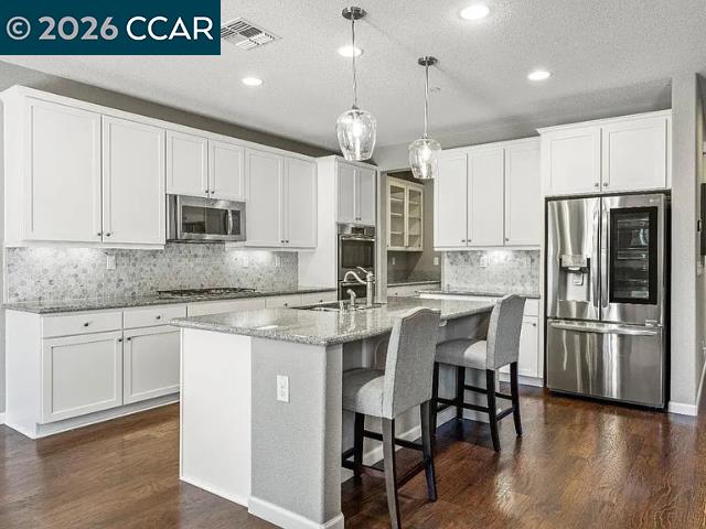 5525 Mossy Stone Way Rancho Cordova, CA 95742 - Photo 7 of 31 a kitchen with stainless steel appliances granite countertop a sink a stove a refrigerator and island with wooden floor