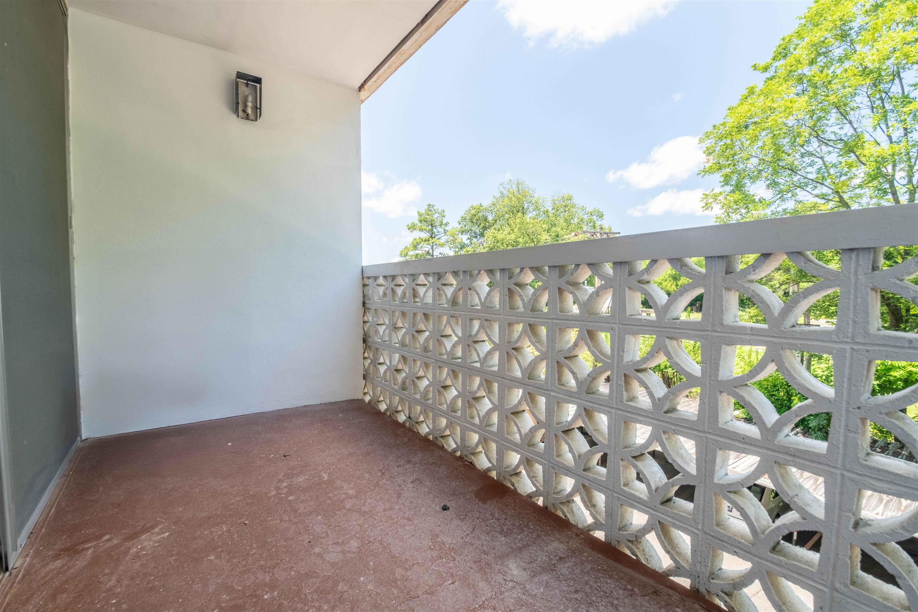 3080 Walnut Grove Road, Unit 306 Memphis, TN 38111 - Photo 6 of 18 Balcony featuring a decorative block privacy screen, wall-mounted lighting fixture, and a durable floor surface