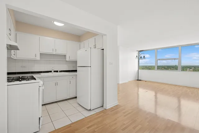 a kitchen with a refrigerator a stove top oven and white cabinets