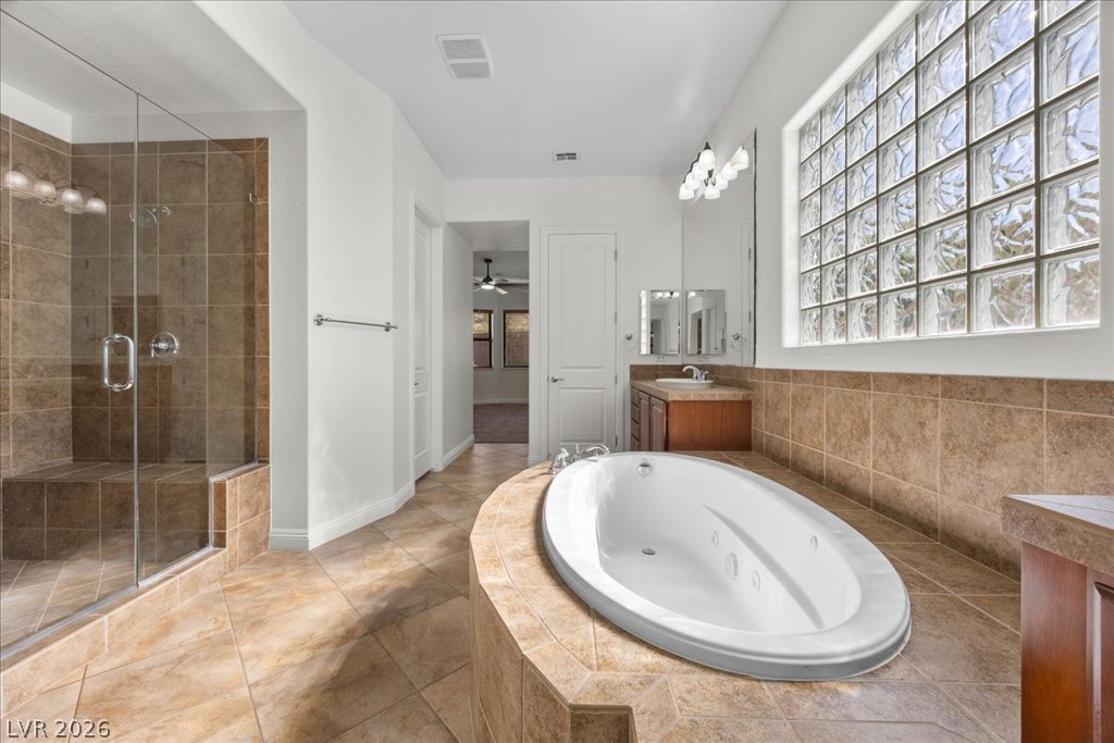 2125 De Rouge Avenue Henderson, NV 89044 - Photo 49 of 96 Indulge in relaxation within this primary bathroom, featuring a jetted tub and a separate glass-enclosed shower.