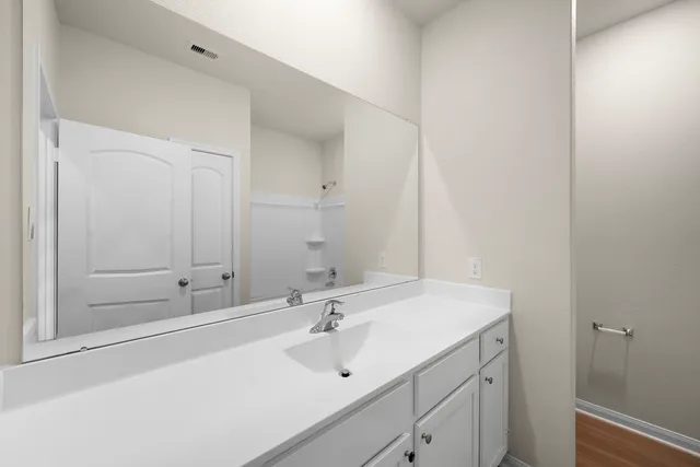 a view of an empty room with kitchen and window