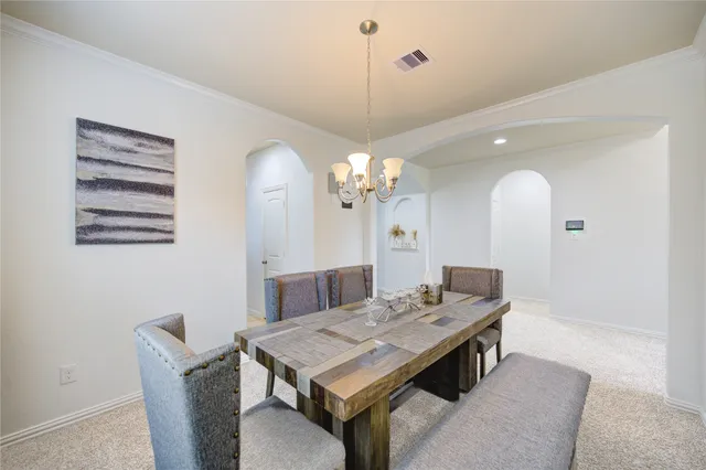 a living room with a table chairs and a chandelier